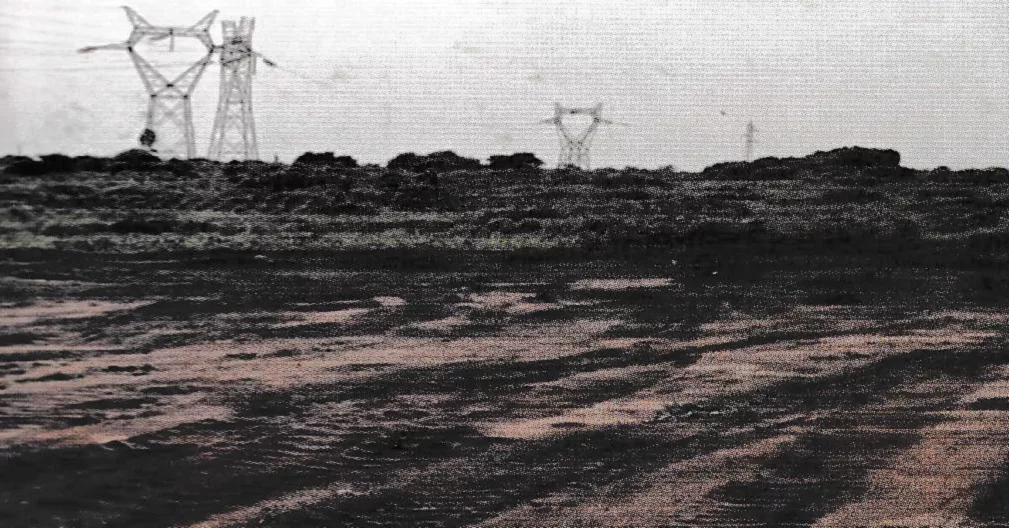 Grande parcelle de terrain nivelée, lignes à haute tension à l’horizon